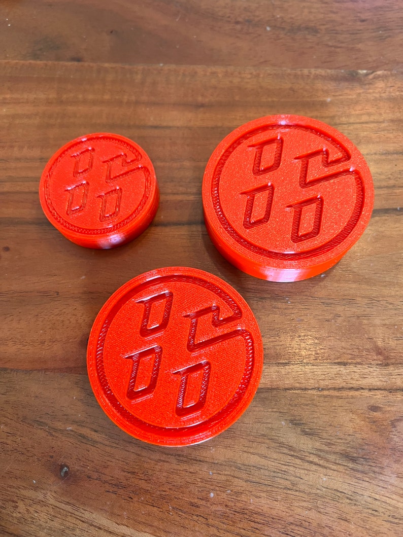 May include: Three red plastic circular coasters with a raised embossed Toyota logo. The coasters are different sizes.