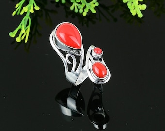 May include: A silver ring with a red stone design. The ring has a large teardrop-shaped stone and a smaller round stone.