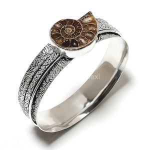 Puede incluir: Pulsera de plata con un diseño adornado y una pieza central de fósil de amonita marrón.