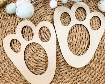 May include: Two wooden paw print cutouts, perfect for Easter decor. The light-colored wood contrasts with the woven background and pastel Easter eggs. These decorative paw prints add a touch of whimsy to any spring celebration.