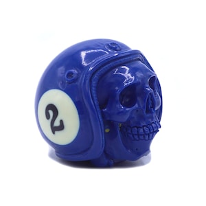Puede incluir: Una calavera azul con un casco azul con un círculo blanco y el número "2" en él.