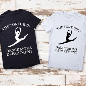 May include: Two t-shirts with the text "The Tortured Dance Moms Department" and a silhouette of a dancer in a split. One shirt is black and the other is white.