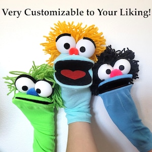 May include: Three sock puppets with yarn hair and large white eyes. The left is green with a blue nose, the center is light blue with yellow hair and a red nose, and the right is blue with black hair and a pink nose. Text reads: Very Customizable to Your Liking!