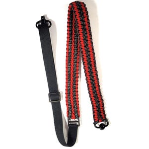 Può includere: Un cinturino per fucile in paracord rosso e nero con un moschettone nero a un'estremità e un gancio girevole nero all'altra estremità.