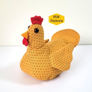 May include: A handmade stuffed chicken with a yellow polka dot pattern. The chicken has a red comb and wattle, an orange beak, and large black eyes. The image includes a yellow hexagon with the text "PDF Pattern".