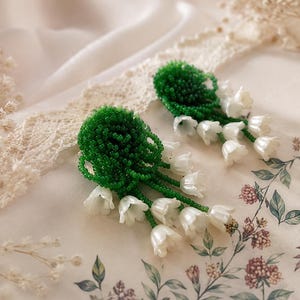 Brincos artesanais com miçangas em formato de lírio-do-vale, joias florais.