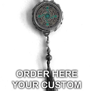 Pu&ograve; includere: Un ciondolo talismano magico color argento con un design circolare dettagliato in verde acqua e argento. Il ciondolo ha una catena di perline e un nappa nera. Il testo "ORDER HERE YOUR CUSTOM MAGIC TALISMAN" &egrave; visualizzato sotto.