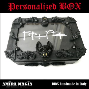 May include: Black wooden box with a glass top and ornate details. The box features a bat design and the text "T?T-I?F" inside the glass. The box is handmade in Italy.
