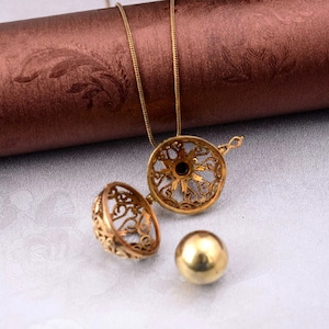 May include: A gold-tone necklace with a cage-like pendant that opens to reveal a small gold ball. The pendant is intricately designed with a filigree pattern.