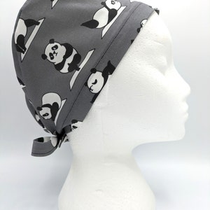 Può includere: Cappello chirurgico grigio con un motivo ripetuto di panda neri e bianchi che fanno pose di yoga.