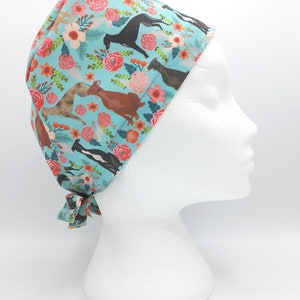 May include: A turquoise blue surgical scrub hat with a floral pattern featuring greyhounds and pink flowers.