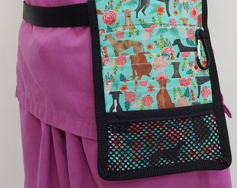 May include: A black fabric belt with a turquoise and floral print pouch attached. The pouch has multiple pockets and a mesh pocket. The pouch is worn on a person's waist.