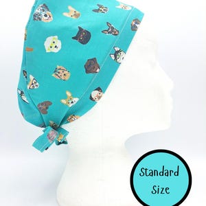 May include: A teal surgical scrub cap with a repeating pattern of dog faces wearing glasses. The cap is tied at the back and displayed on a white mannequin head. The text "Standard Size" is in a teal circle.