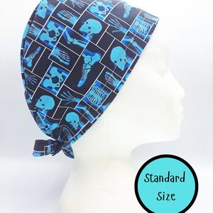 Puede incluir: Un gorro quirúrgico azul marino con un patrón repetido de imágenes de rayos X en azul claro de cráneos, huesos y articulaciones. El gorro está atado en la parte posterior y se muestra en una cabeza de maniquí blanca. El texto "Standard Size" está en un círculo turquesa.