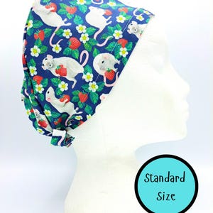 Peut inclure: Un bonnet de chirurgien bleu marine orné d'un motif fantaisiste de souris blanches, de fraises rouges et de fleurs blanches. Le bonnet, de taille standard, est conçu pour être porté lors des interventions médicales.