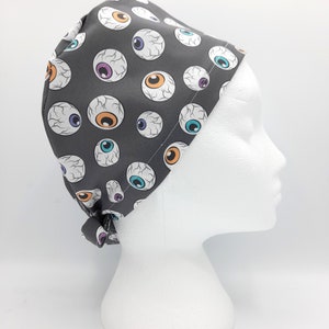 Puede incluir:  gorro de quirófano gris con un patrón de ojos de dibujos animados coloridos.