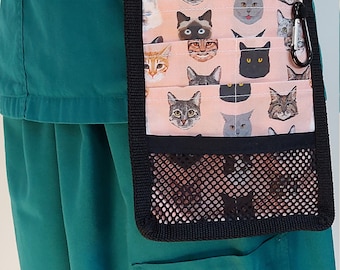 Peut inclure: Un haut de blouse turquoise avec une ceinture noire et une poche utilitaire à thème chat rose et noir avec une poche en filet. La poche a un mousqueton noir.