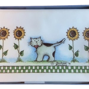 May include: A white cat with black spots and a red heart on its chest walks past a row of four yellow sunflowers with brown centers. The sunflowers are growing in a green field with a green and white checkered border at the bottom of the image. The text "Barbara" and "1994" is written in the bottom right corner of the image.