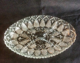 May include: A clear glass serving dish with three divided sections. The dish has a scalloped edge and a starburst pattern.