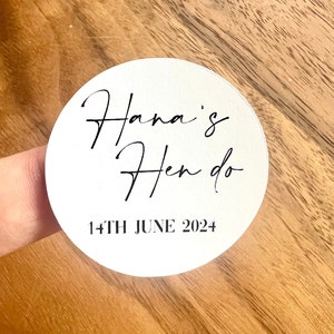 May include: White round sticker with black text that reads "Hana's Hen do 14th June 2024".