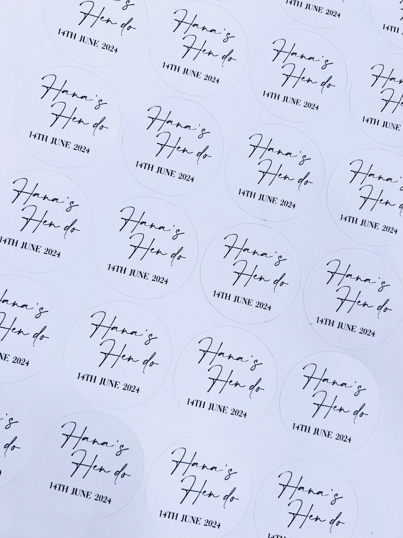 May include: A collection of white round stickers with black text that says "Hana's Hen do" and the date "14th June 2024".