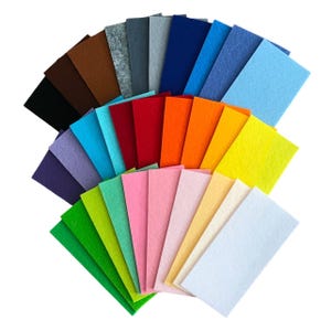 Könnte beinhalten: Eine Sammlung farbiger Filzbögen, fächerförmig angeordnet. Die Farben umfassen Braun-, Grau-, Blau-, Rot-, Orange-, Gelb-, Grün-, Rosa- und Weißtöne. Das Filzmaterial scheint eine gleichmäßige Dicke und Textur aufzuweisen.