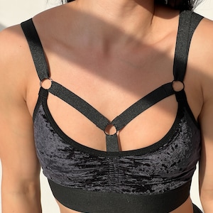 Black velvet sports bra with a criss-cross strap design and silver metal rings.