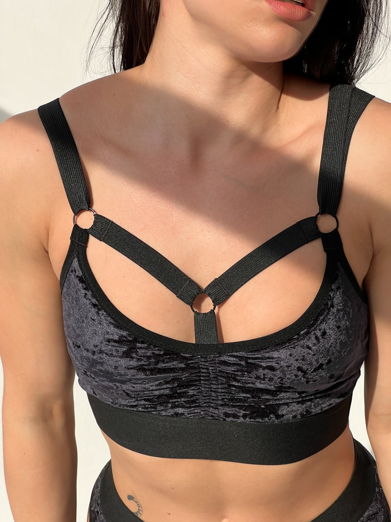 Black velvet sports bra with a criss-cross strap design and silver metal rings.