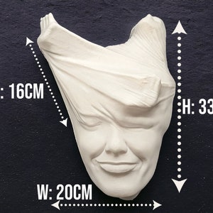 May include: White plaster sculpture of a face with fabric draped over the head. The sculpture is 33 cm tall, 20 cm wide, and 16 cm deep.