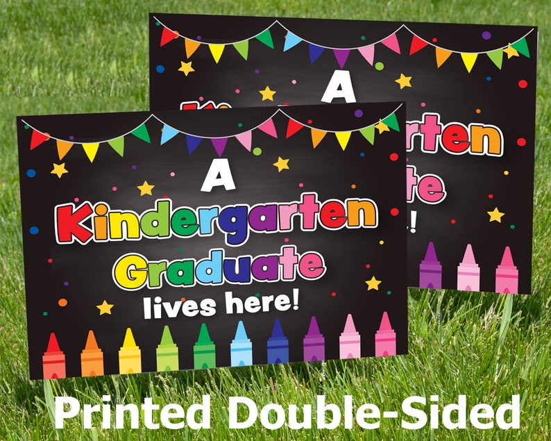 May include: Two black chalkboard signs with colorful decorations. The top sign says "A Kindergarten Graduate!" The bottom sign says "A Kindergarten Graduate lives here!" Both signs have a row of colorful crayons at the bottom.
