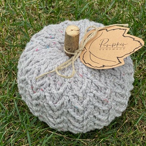 May include: A gray crocheted pumpkin with a brown leaf tag that says "Pumpkin Handmade".