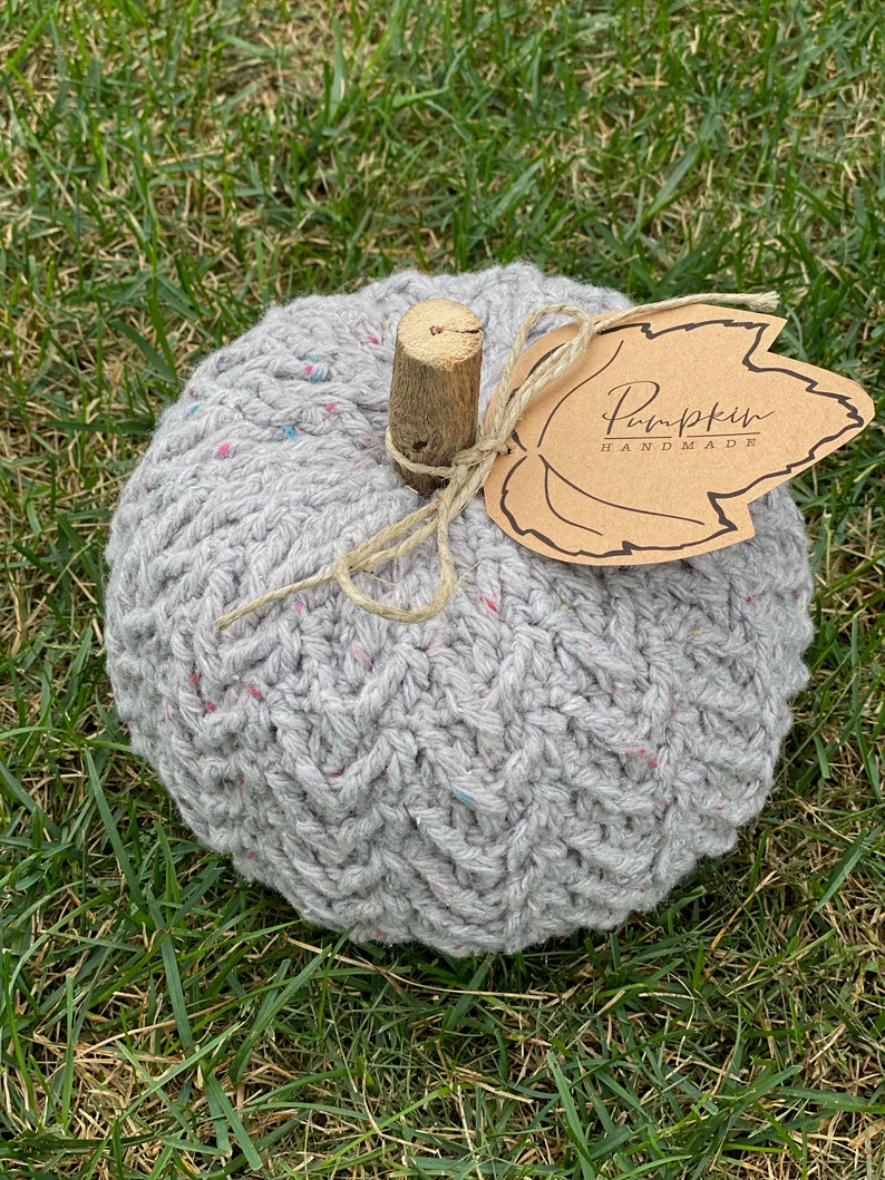 May include: A gray crocheted pumpkin with a brown leaf tag that says "Pumpkin Handmade".
