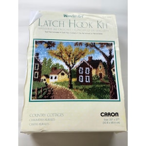 以下が含まれることがあります： Caron社製WonderArtラッチフックキット「Country Cottages」。パッケージには家、木々、小道の風景イラストが描かれています。キットのサイズは50.8cm x 68.6cmです。パッケージのテキストには「Latch Hook Kit」と記載されています。