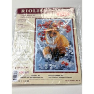 May include: A Riolis cross stitch kit in a plastic package featuring a printed illustration of a fox sitting among red leaves and blue flowers. The packaging includes the text Riolis, Cross stitch kit, and a finished size of 8.25 x 11.75 inches.