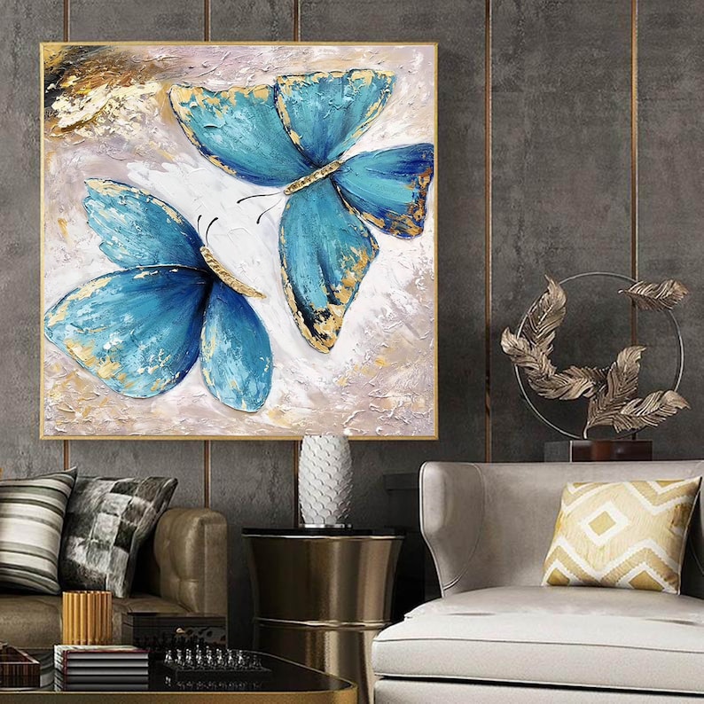 May include: A painting of two blue butterflies with gold accents on a white background. The butterflies are painted in a realistic style and have intricate details.