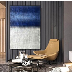 Puede incluir: Pintura abstracta con un esquema de color azul y blanco. La pintura est&aacute; colgada en una pared en un ambiente de sala de estar moderna. La pintura est&aacute; enmarcada y tiene una superficie texturizada.