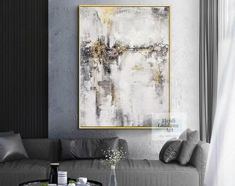 May include: Abstract art painting with a gold frame. The artwork features a textured design in shades of white, gray, black, and gold. The painting is displayed above a gray sofa in a modern living room setting.