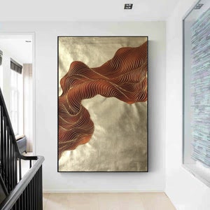 May include: Abstract wall art featuring a flowing, wavy design in shades of gold and brown. The artwork is painted on a canvas and has a modern, minimalist style.