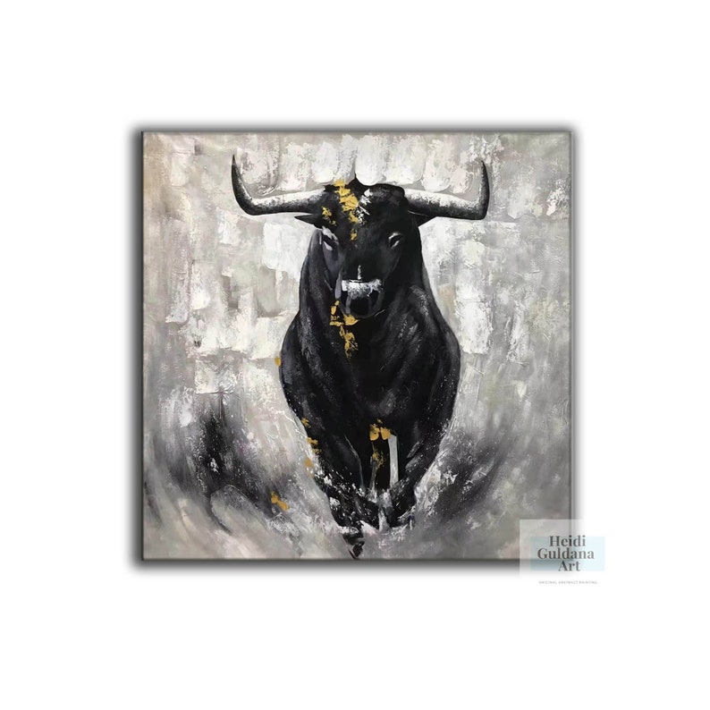May include: A black bull painting with gold accents on a textured gray and white background. The bull is the focal point, depicted in a charging pose. The artwork is signed "Heidi Guldana Art".