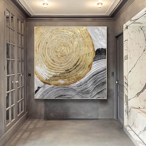 May include: Abstract wall art featuring a large gold circle with concentric rings on a white and gray background.