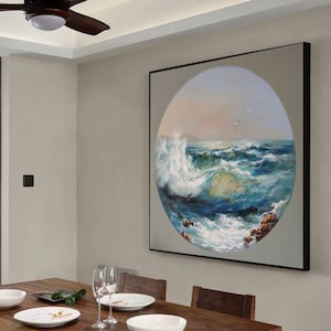 May include: A framed painting of a seascape with a large wave crashing in the foreground. The painting is in a circular frame and is set against a light gray wall.