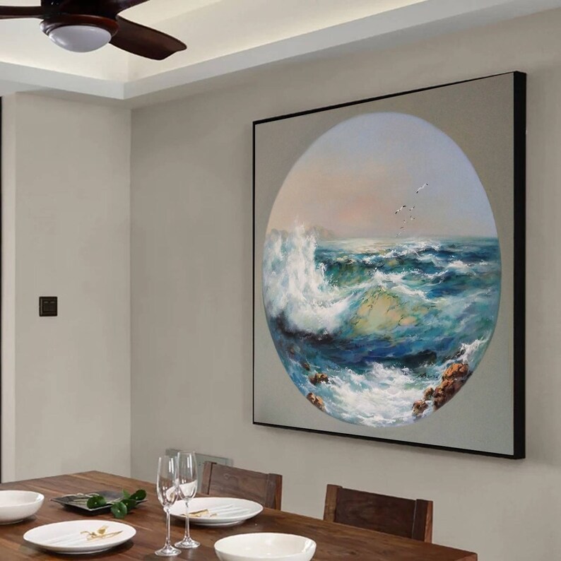 May include: A framed painting of a seascape with a large wave crashing in the foreground. The painting is in a circular frame and is set against a light gray wall.