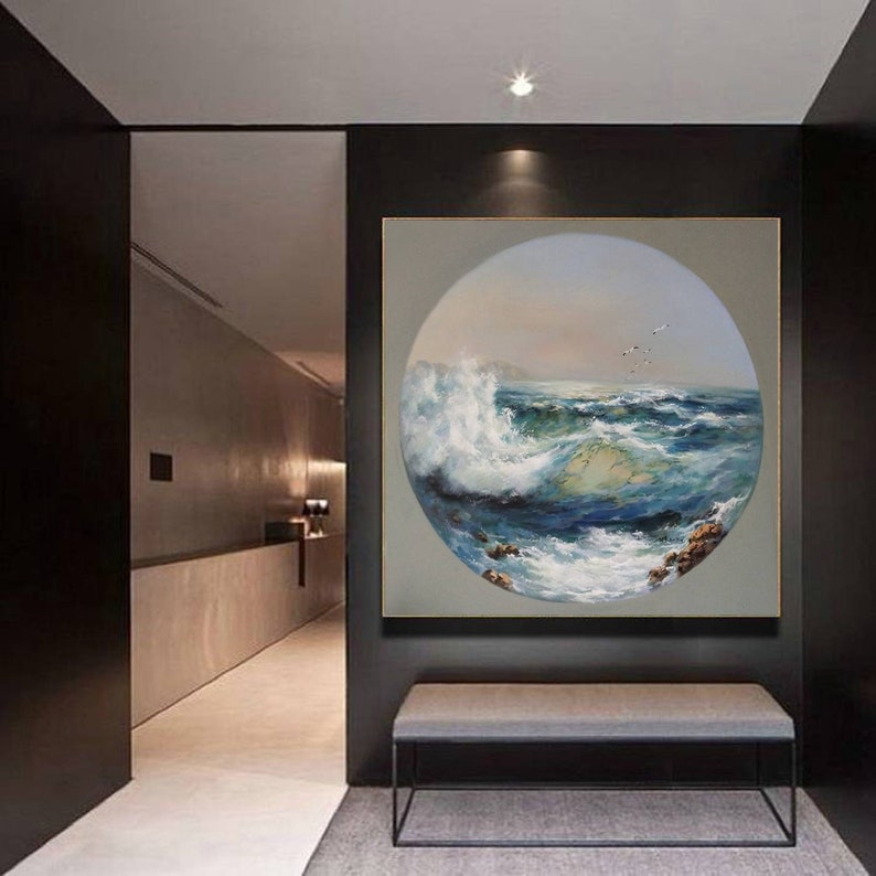 May include: A circular painting of a seascape with a large wave crashing in the foreground. The painting is framed in a black frame and hangs on a wall in a modern hallway.