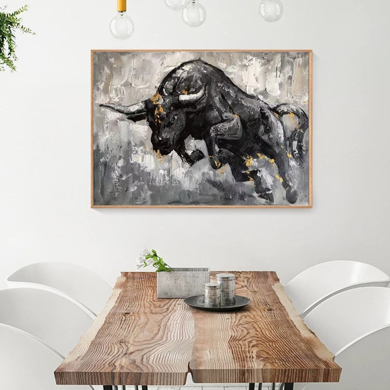 May include: A black and white abstract painting of a bull charging forward with gold accents. The bull is painted in a textured style with a dramatic pose.