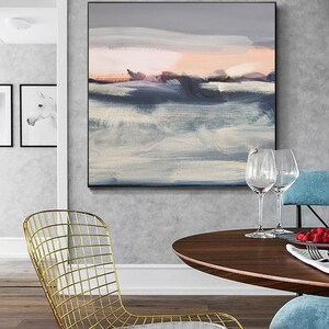 May include: Abstract painting with a gray, white, and pink color scheme. The painting depicts a landscape with a horizon line and clouds. The painting is framed in a black frame and is hanging on a gray wall.
