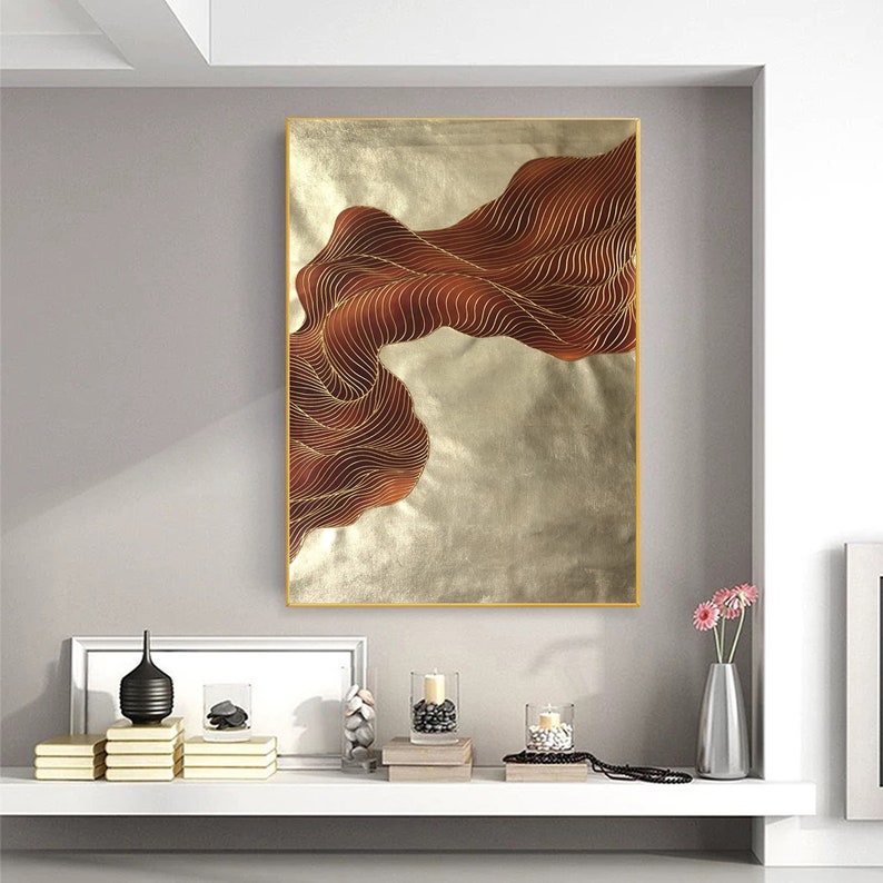 May include: Abstract wall art featuring a flowing, brown, wavy design on a gold background. The artwork is framed in a thin, gold frame.
