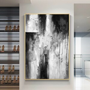 Puede incluir: Pintura abstracta en blanco y negro con marco dorado. La pintura presenta pinceladas gruesas y goteos de pintura.