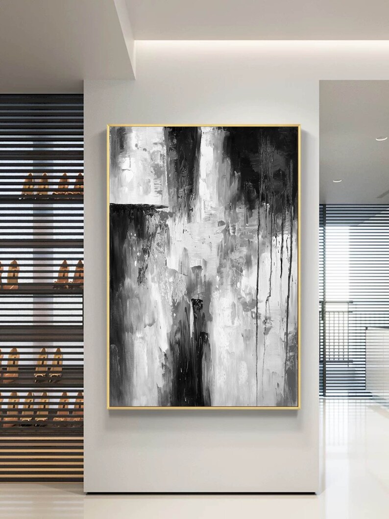 Puede incluir: Pintura abstracta en blanco y negro con marco dorado. La pintura presenta pinceladas gruesas y goteos de pintura.