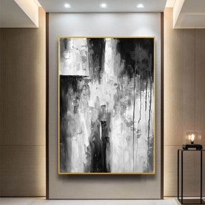 Puede incluir: Pintura abstracta en blanco y negro con pinceladas gruesas y goteos de pintura. La pintura est&aacute; enmarcada en un marco dorado.