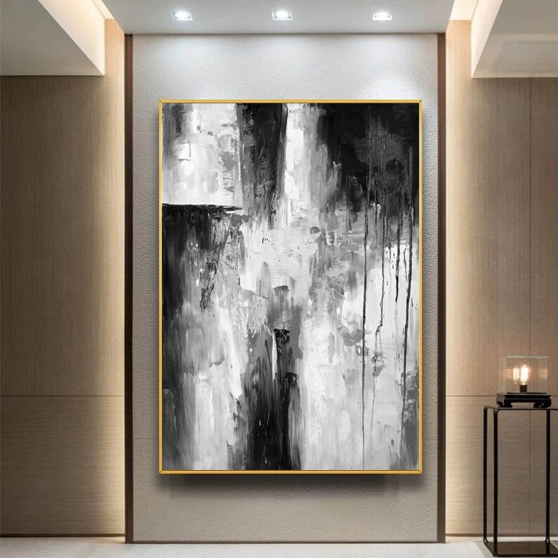 Puede incluir: Pintura abstracta en blanco y negro con pinceladas gruesas y goteos de pintura. La pintura est&aacute; enmarcada en un marco dorado.